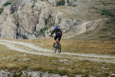 Rear view of man riding bicycle on mountain