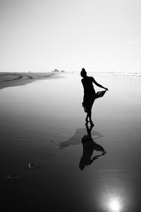 Silhouette woman wading in sea against sky