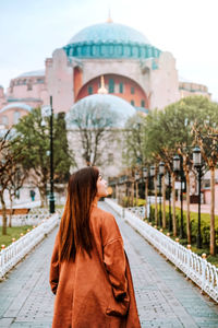 Rear view of woman standing on cross in city