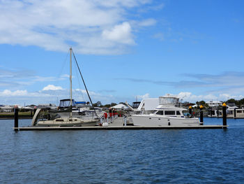 Sailboats moored at harbor against sky