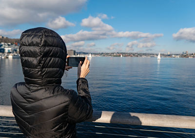 Rear view of man photographing sea against sky