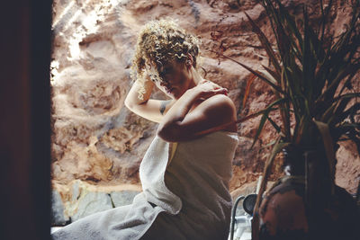 Side view of young woman looking through window