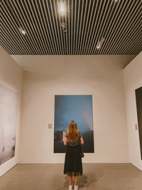 Rear view of woman standing in illuminated building