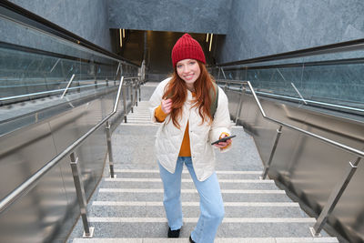 Portrait of young woman standing on escalator