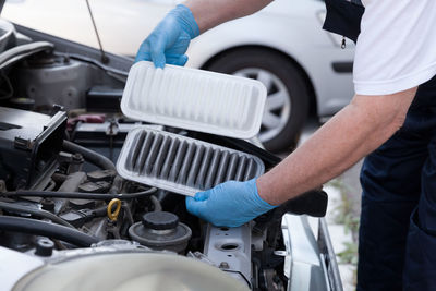 Midsection of mechanic repairing car at garage