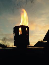 Close-up of fire burning against sky during sunset