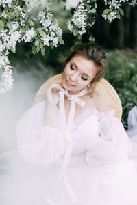 Beautiful bride in a wedding dress walks in a blooming apple-tree park in spring