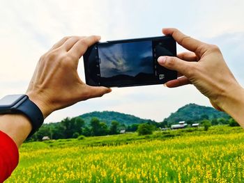 Midsection of man photographing with mobile phone