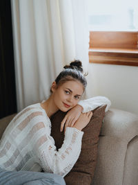 Young woman sitting on sofa at home