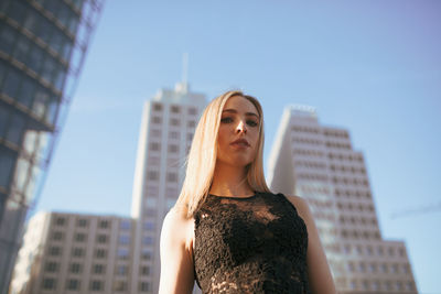 Portrait of beautiful woman standing against buildings