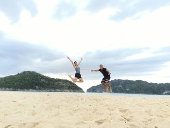 People playing on beach against sky