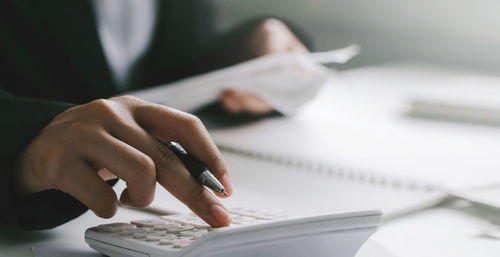 Close up of businessman or accountant hand holding pen working on calculator to calculate business 