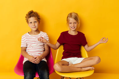 Portrait of happy family sitting on sofa against yellow wall