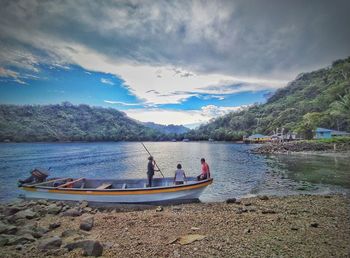 People on boat in lake against sky