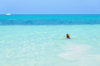 Person in sea against clear blue sky