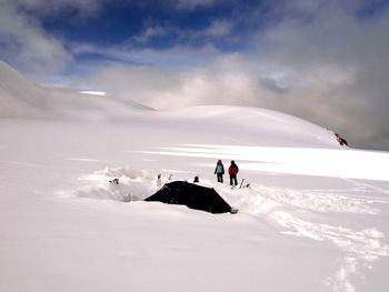 People standing on snow field against sky