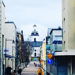 Road by buildings against sky in city