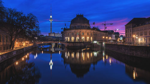 Illuminated fernsehturm and historic building at night