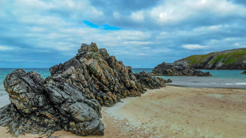 Rock formations on beach against sky