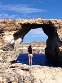 Man standing on rock formation in sea