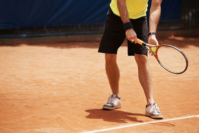 Midsection of man playing tennis