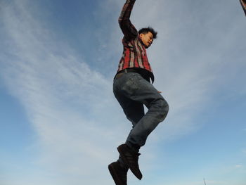 Low angle view of man jumping against sky