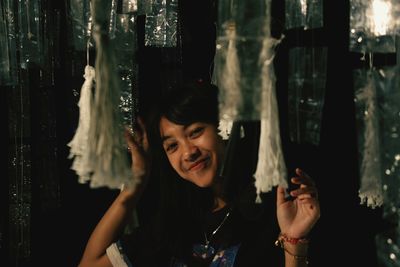 Close-up of woman standing against curtain at night