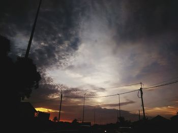 Silhouette of power lines against cloudy sky