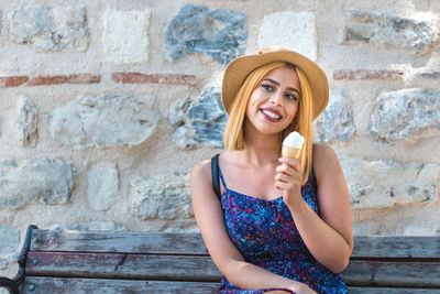 Portrait of a smiling young woman sitting against wall