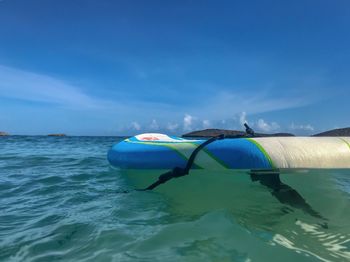 Paddleboard on sea against blue sky