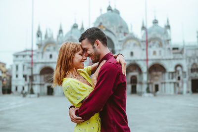 Young couple embracing against cathedral in city