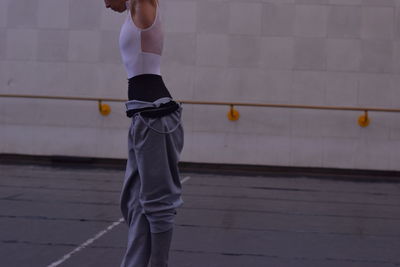 Midsection of ballet dancer standing against wall