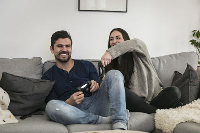 Happy couple enjoying while playing video game on sofa at home