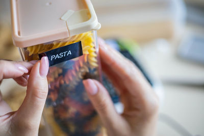 Cropped hand of woman labeling pasta container