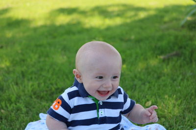 Cheerful baby boy sitting on grassy field