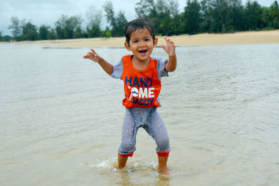 Portrait of smiling boy dancing in sea