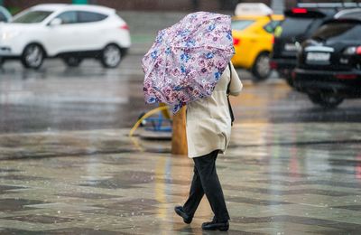 Rear view of woman with umbrella walking on wet road