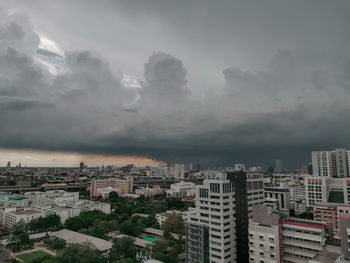 High angle view of buildings in city against storm clouds