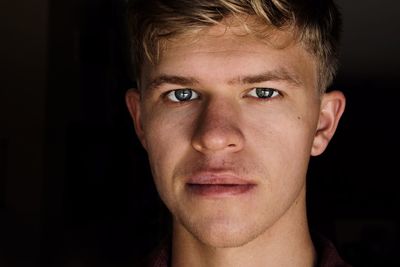 Close-up portrait of young man against black background