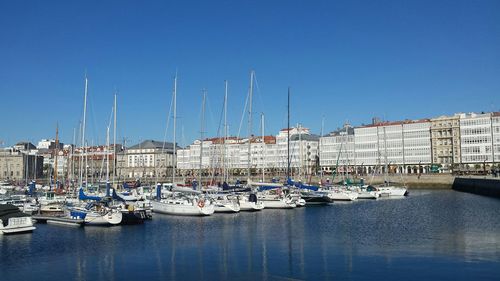 Sailboats moored at harbor against clear blue sky