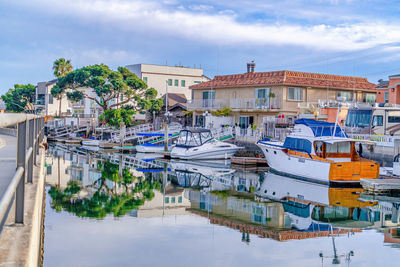 Sailboats moored in canal against buildings in city