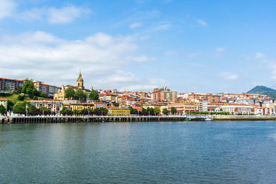 Buildings by river against sky