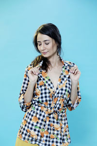 Young woman standing against blue background