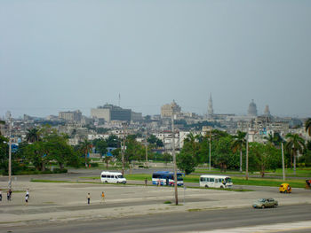 Cars on road by buildings against clear sky