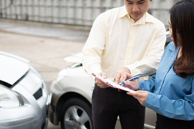 Midsection of man holding woman standing in car