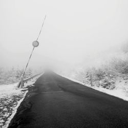 Road amidst snowcapped landscape against sky during winter