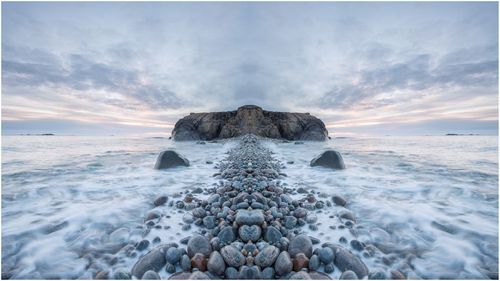 Digital composite image of rocks in sea against sky