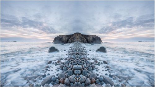 Digital composite image of rocks in sea against sky