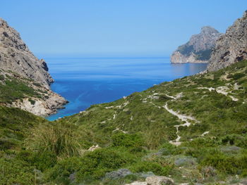 Scenic view of sea and mountains against clear blue sky