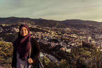 Portrait of young woman standing against cityscape